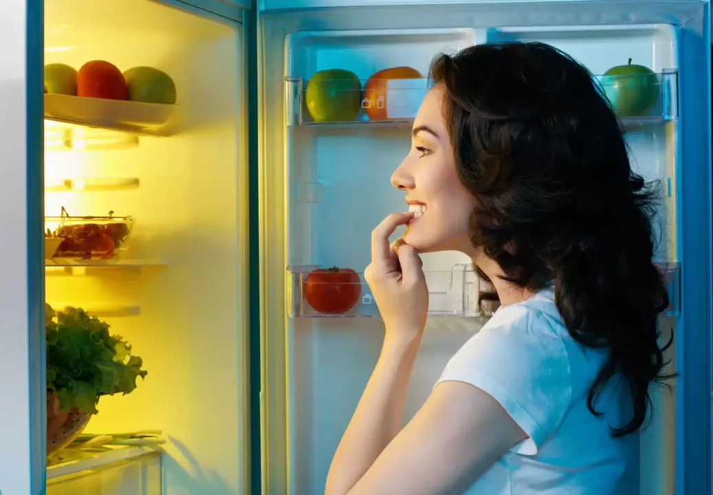 Fata se uită în frigider în timpul pierderii rapide în greutate